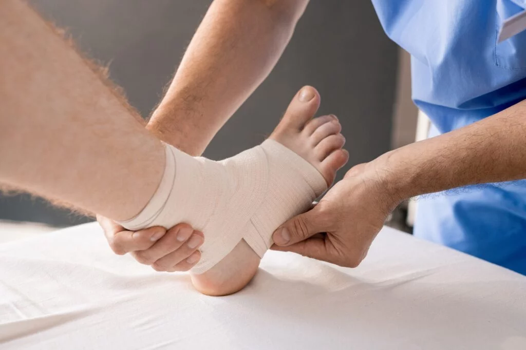 Healthcare professional wrapping a bandage around a patient's ankle.