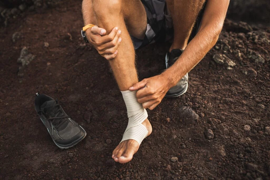 Person wrapping a bandage around their ankle outdoors.