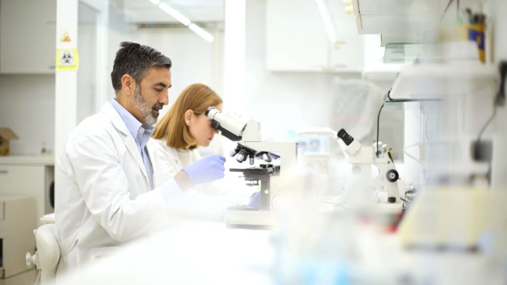 Healthcare professionals working with microscopes in a laboratory.