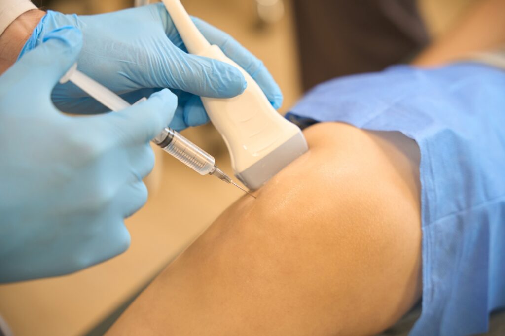 Doctor performing ultrasound guided injections on a patient