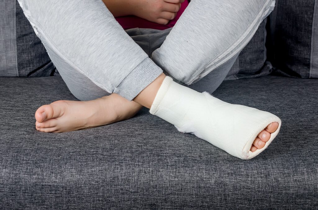 Person sitting on a couch with a foot cast.